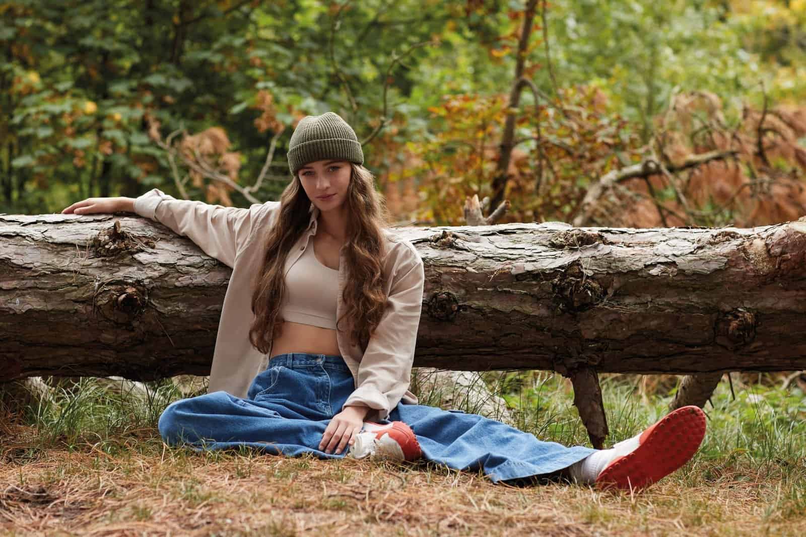 Image of young woman in beanie relaxing outdoors in autumn forest.