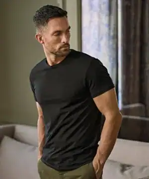 Man wearing a black stretch T-shirt, casual indoor setting.