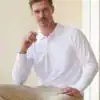 Man wearing a white long sleeve polo shirt, casual style, indoor setting.