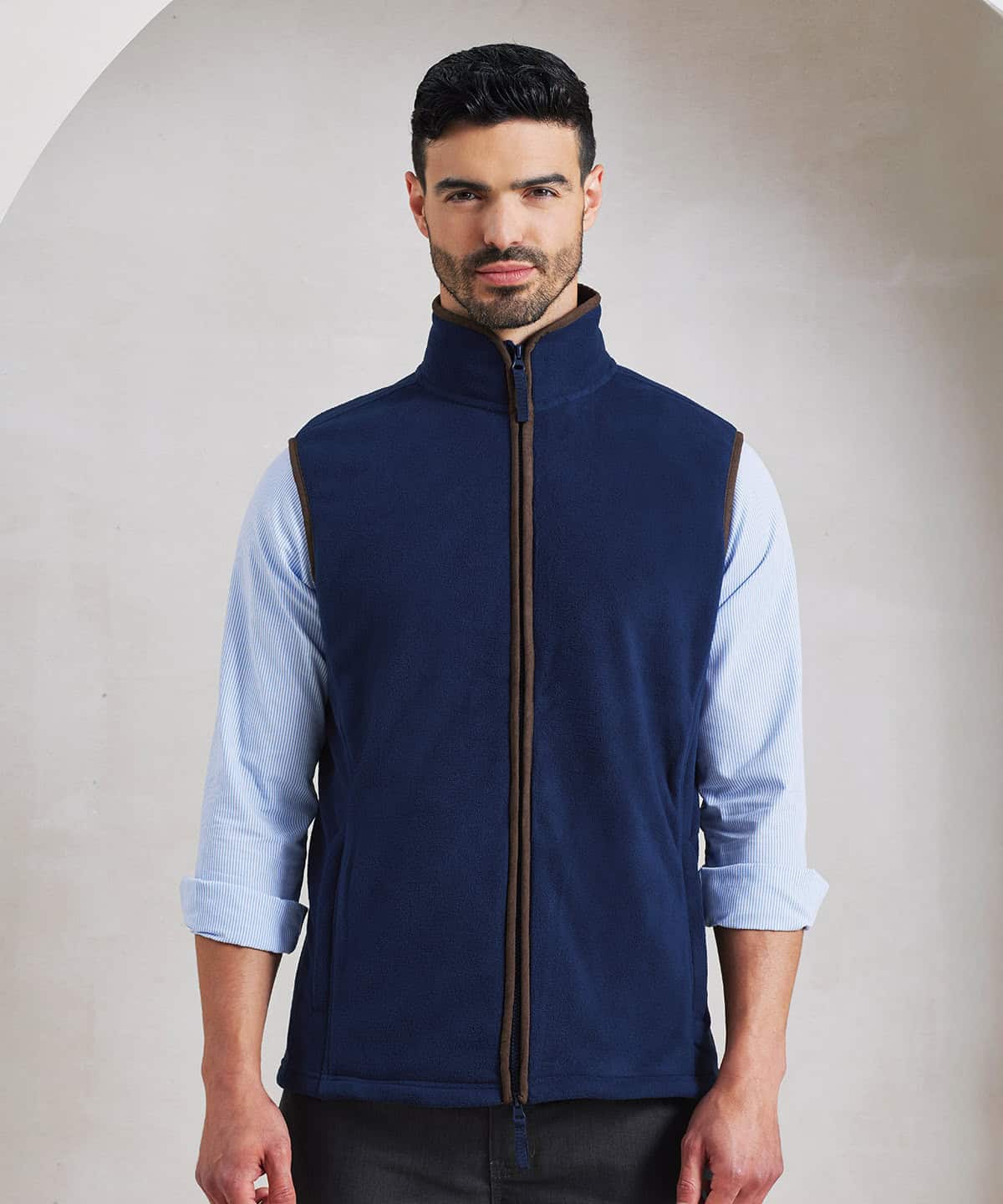 Man wearing navy blue embroidered fleece gilet with high collar and zip closure.