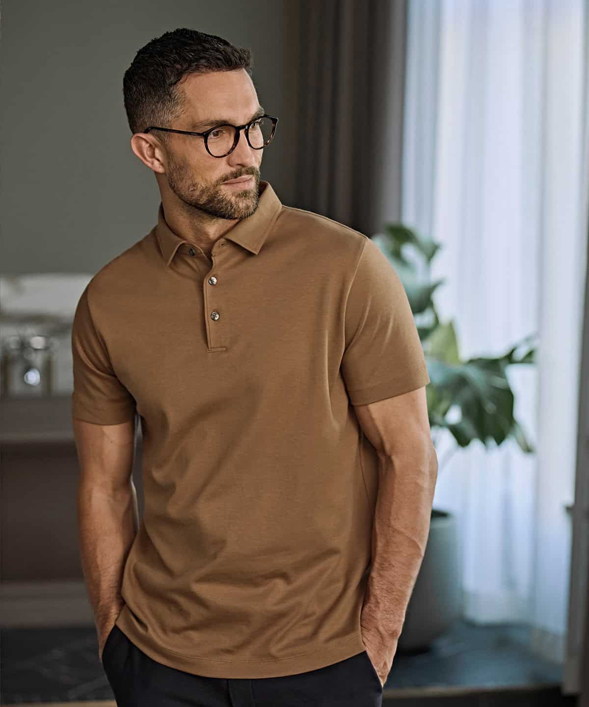 Man wearing a Pima cotton polo shirt in a modern indoor setting.